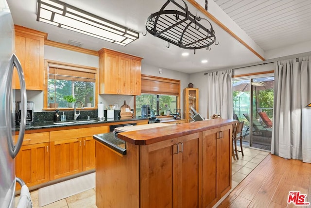 kitchen with plenty of natural light, stainless steel fridge, sink, and a kitchen island