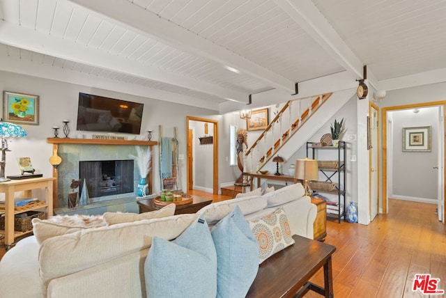 living room with beamed ceiling, wood ceiling, a high end fireplace, and light hardwood / wood-style flooring