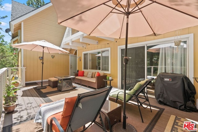 wooden terrace with area for grilling and an outdoor living space with a fire pit