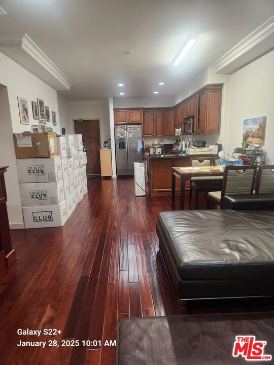 kitchen featuring dark hardwood / wood-style flooring, crown molding, and appliances with stainless steel finishes