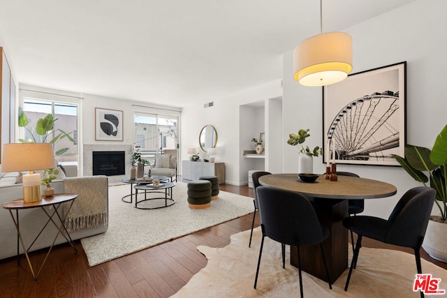 dining space with hardwood / wood-style flooring and a fireplace