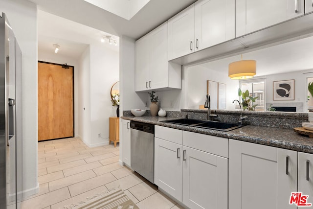 kitchen featuring stainless steel appliances, white cabinetry, sink, and dark stone counters