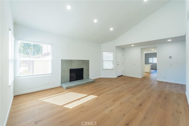 unfurnished living room with a fireplace, high vaulted ceiling, and light wood-type flooring