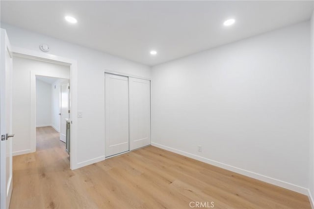 unfurnished bedroom with light wood-type flooring and a closet