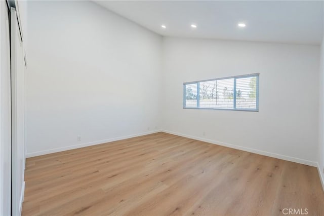 empty room featuring light hardwood / wood-style floors and vaulted ceiling