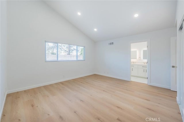 interior space featuring high vaulted ceiling, light hardwood / wood-style floors, and ensuite bath