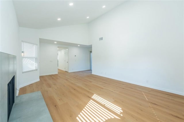 unfurnished living room with high vaulted ceiling and light hardwood / wood-style flooring