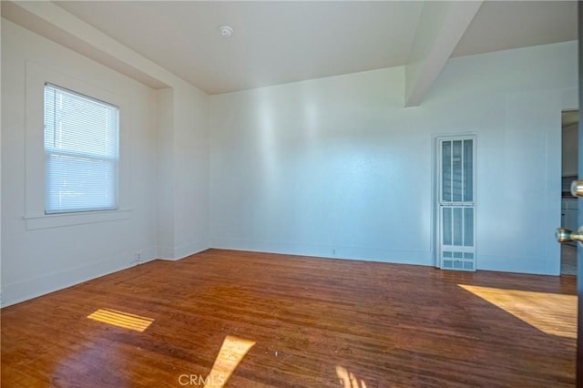 empty room with hardwood / wood-style flooring and beam ceiling