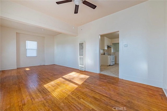 spare room featuring beam ceiling, ceiling fan, and light wood-type flooring