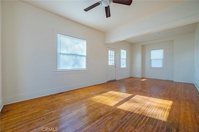 empty room with beamed ceiling, ceiling fan, and wood-type flooring