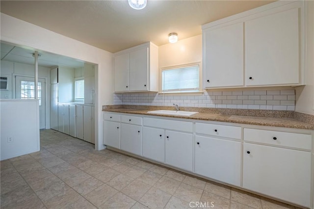 kitchen featuring sink, decorative backsplash, and white cabinets