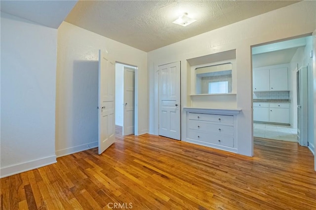 unfurnished bedroom with light hardwood / wood-style flooring and a textured ceiling