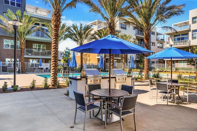 view of patio with a community pool, a grill, and exterior kitchen