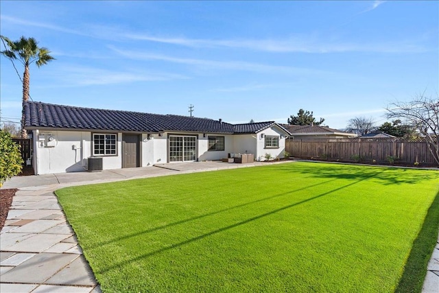 back of property with central air condition unit, a patio area, and a lawn