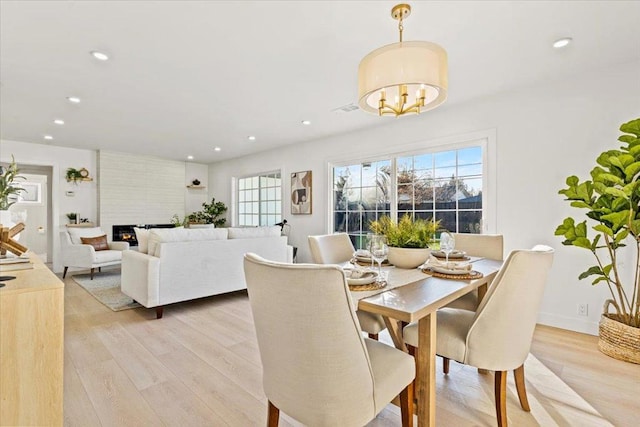 dining room featuring a fireplace, light hardwood / wood-style floors, and a notable chandelier