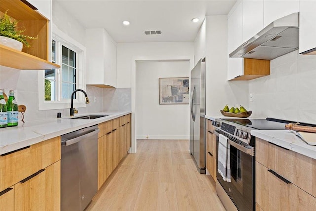 kitchen featuring white cabinetry, appliances with stainless steel finishes, wall chimney exhaust hood, and light stone counters