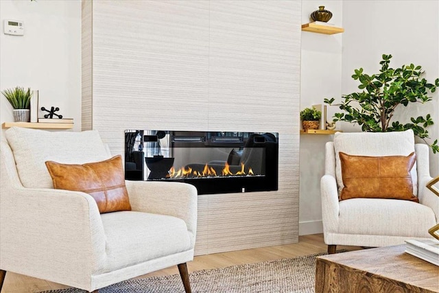 sitting room featuring hardwood / wood-style flooring and a multi sided fireplace