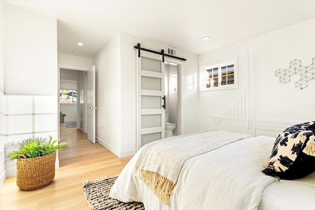 bedroom featuring wood-type flooring and a barn door