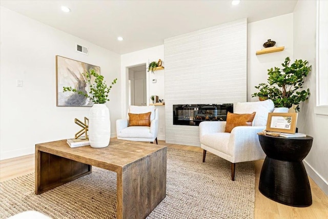 living area featuring hardwood / wood-style flooring and a large fireplace