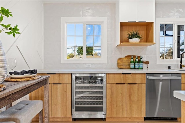 bar with beverage cooler, dishwasher, sink, and white cabinets