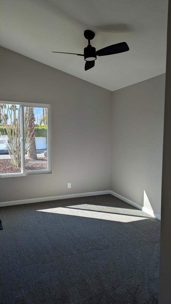 carpeted spare room featuring ceiling fan