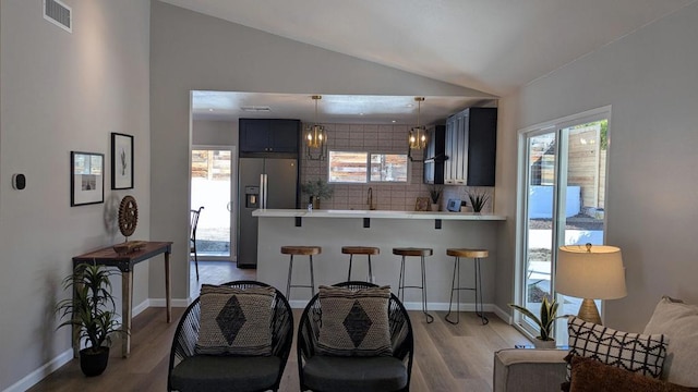 kitchen with blue cabinetry, a kitchen breakfast bar, kitchen peninsula, and decorative backsplash