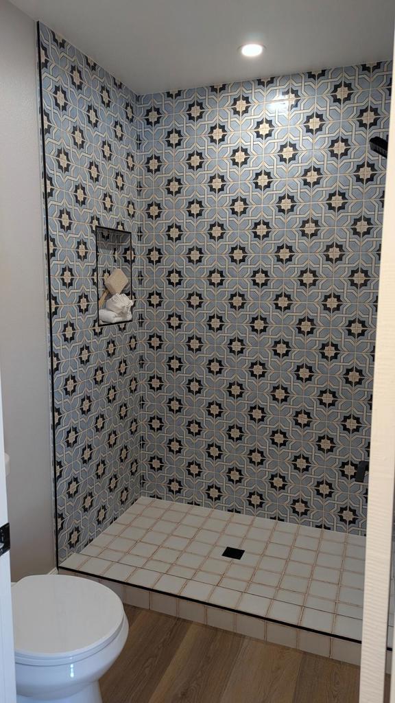 bathroom featuring wood-type flooring, toilet, and a tile shower