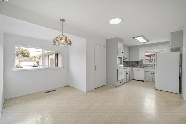 kitchen with pendant lighting, backsplash, and white appliances