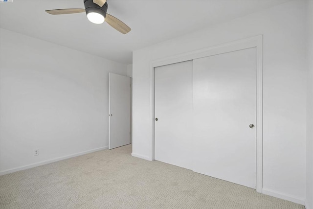 unfurnished bedroom featuring light colored carpet, ceiling fan, and a closet