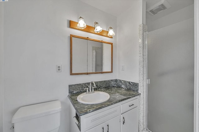 bathroom featuring vanity, toilet, and walk in shower