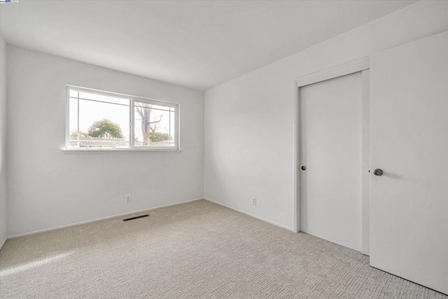 unfurnished bedroom featuring light colored carpet and a closet