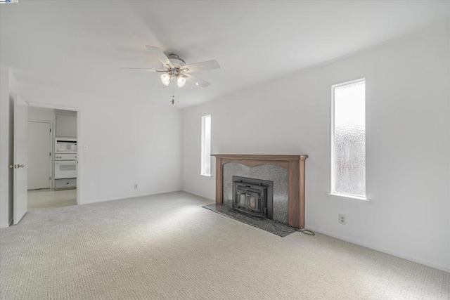 unfurnished living room featuring a healthy amount of sunlight, light carpet, and ceiling fan