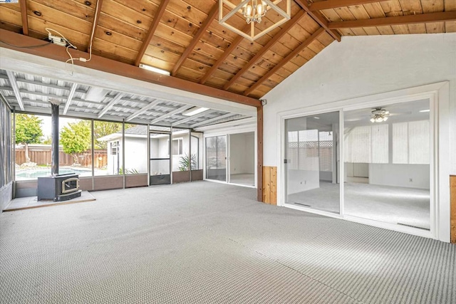 unfurnished sunroom featuring vaulted ceiling with beams, wood ceiling, ceiling fan, and a wood stove