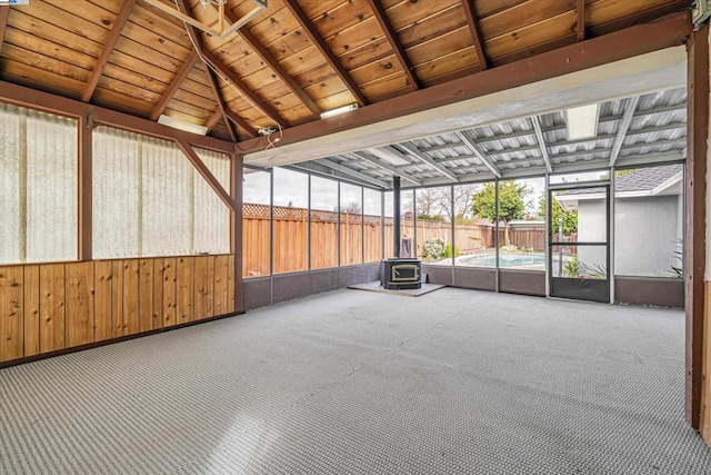 unfurnished sunroom featuring vaulted ceiling with beams, wood ceiling, and a wood stove