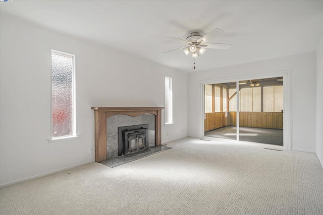 unfurnished living room with ceiling fan, a healthy amount of sunlight, and carpet