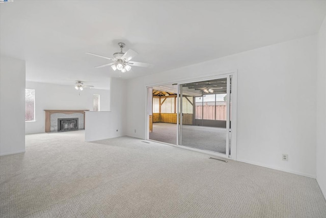 unfurnished living room featuring ceiling fan, a fireplace, and light carpet