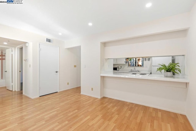 bar featuring tile countertops, sink, white cabinets, white refrigerator, and light hardwood / wood-style floors