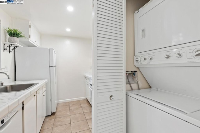 washroom with light tile patterned flooring, stacked washer and dryer, and sink