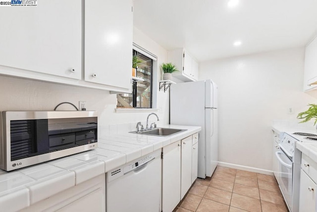 kitchen with sink, tile counters, white cabinets, and white appliances