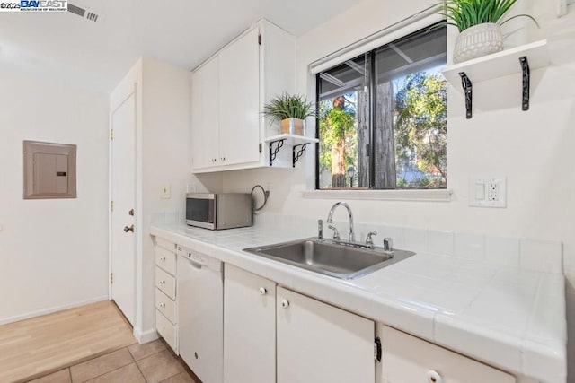 kitchen with white cabinetry, dishwasher, tile counters, and electric panel