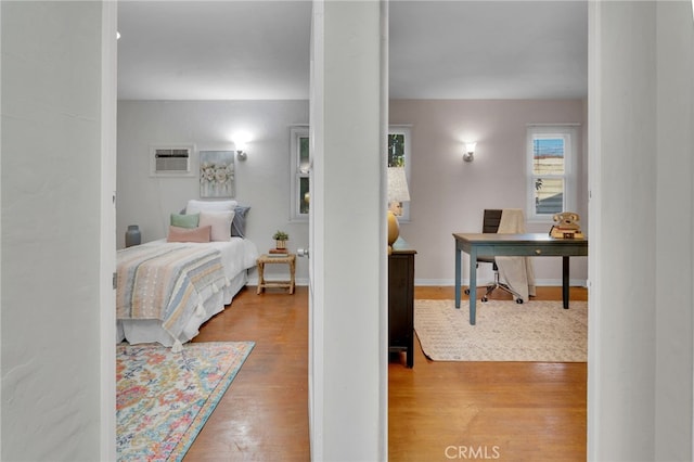 bedroom featuring hardwood / wood-style flooring and an AC wall unit