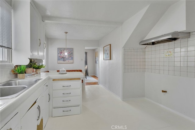 kitchen with white cabinetry, decorative light fixtures, kitchen peninsula, beam ceiling, and wall chimney range hood