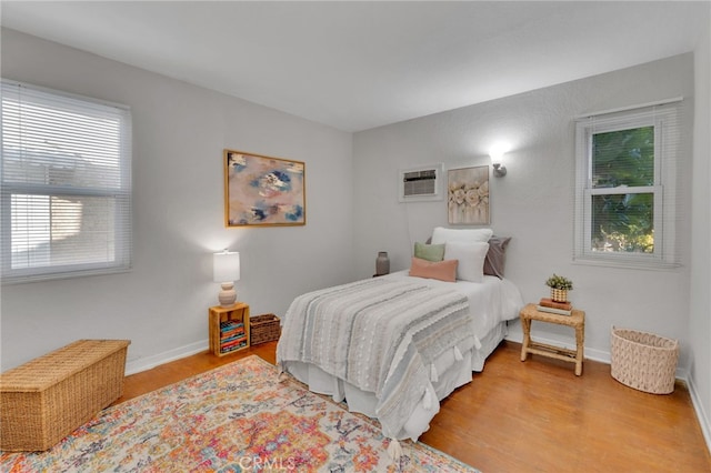 bedroom featuring a wall mounted AC and light hardwood / wood-style flooring