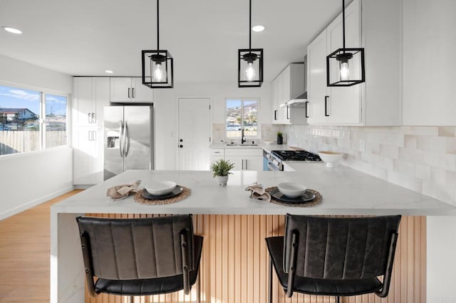 kitchen featuring stainless steel appliances, white cabinetry, pendant lighting, and a kitchen bar