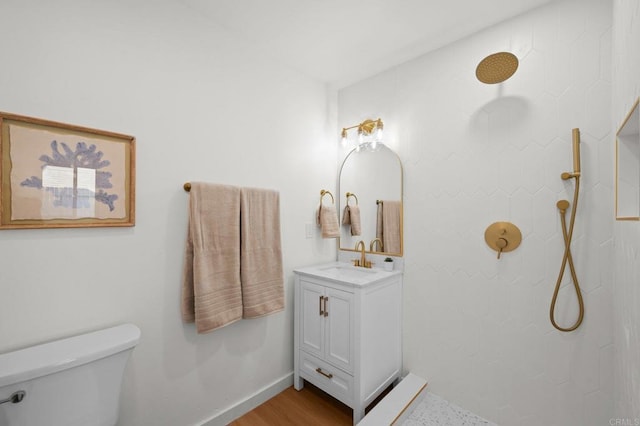 bathroom with vanity, a tile shower, and toilet