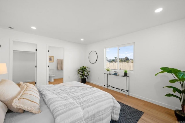 bedroom with ensuite bath and light hardwood / wood-style flooring