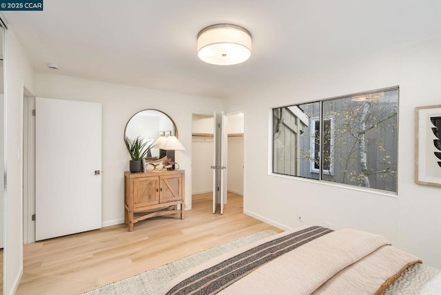 bedroom featuring a closet, a spacious closet, and light hardwood / wood-style flooring