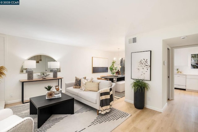 living room featuring an inviting chandelier and light hardwood / wood-style flooring