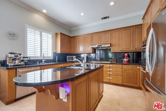 kitchen featuring crown molding, appliances with stainless steel finishes, sink, and a center island with sink