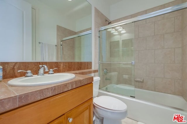 full bathroom with vanity, backsplash, combined bath / shower with glass door, and toilet